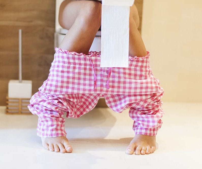 Person auf der Toilette mit heruntergelassener Pyjamahose – Symbolbild für Durchfall bei Antibiotika-Einnahme