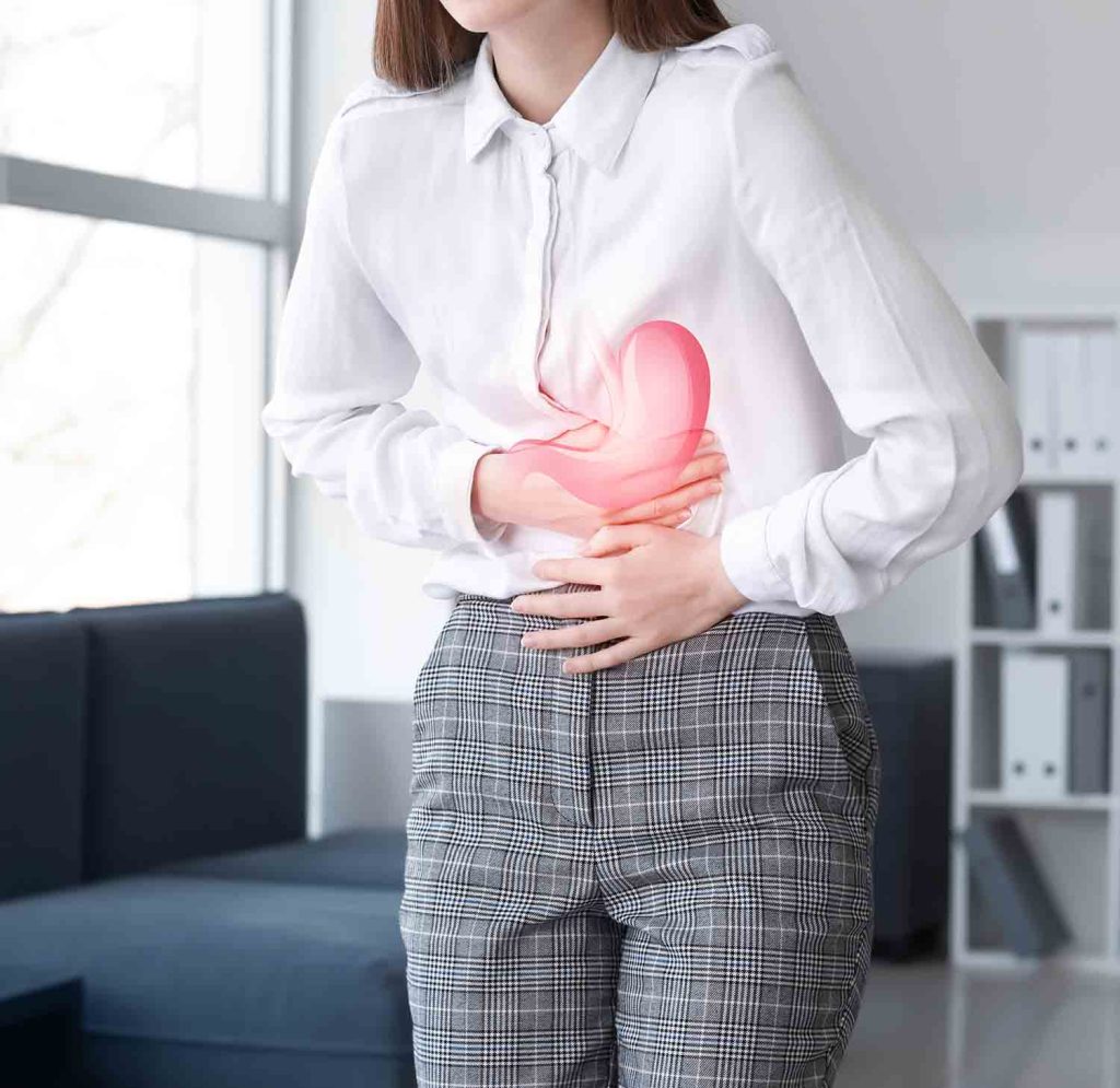 Frau hält sich mit Schmerzen den Magen – Darstellung von Magen-Darm-Beschwerden