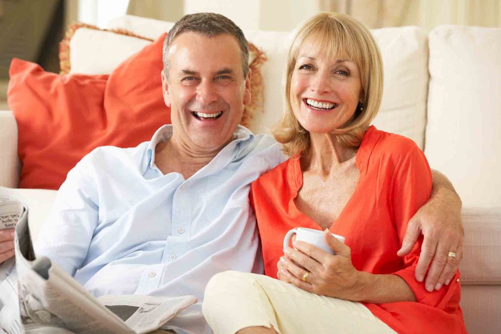 Lachendes älteres Paar auf dem Sofa – Lebensfreude und Gesundheit im Alltag